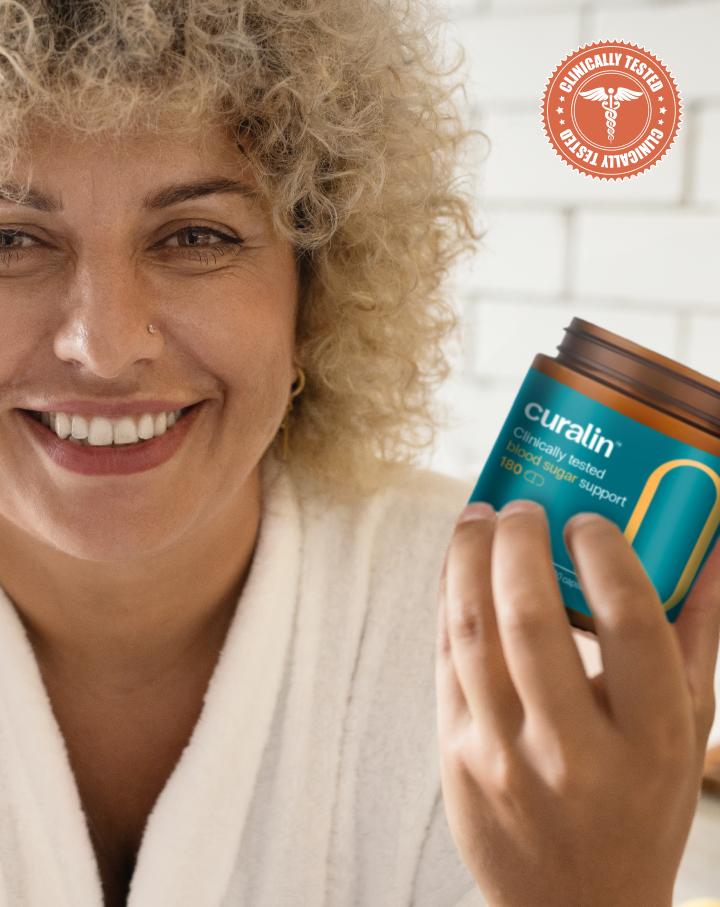 A smiling woman holding a bottle of Curalin, a clinically tested blood sugar support supplement.