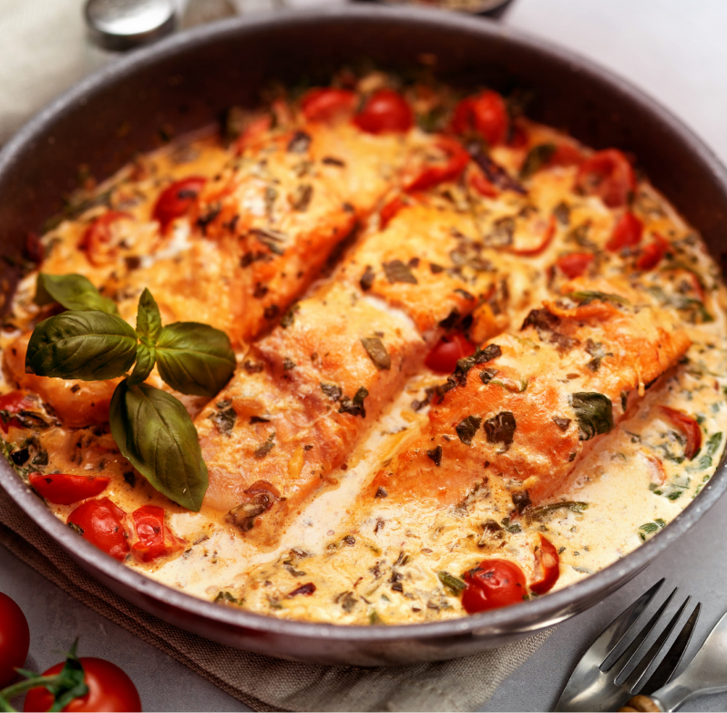 A photo of salmon in a creamy tomato sauce with cherry tomatoes.